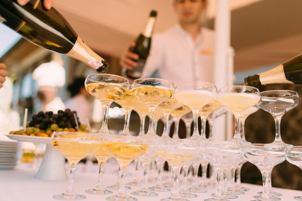 Champagne being elegantly poured into glasses at a festive celebration outdoors.